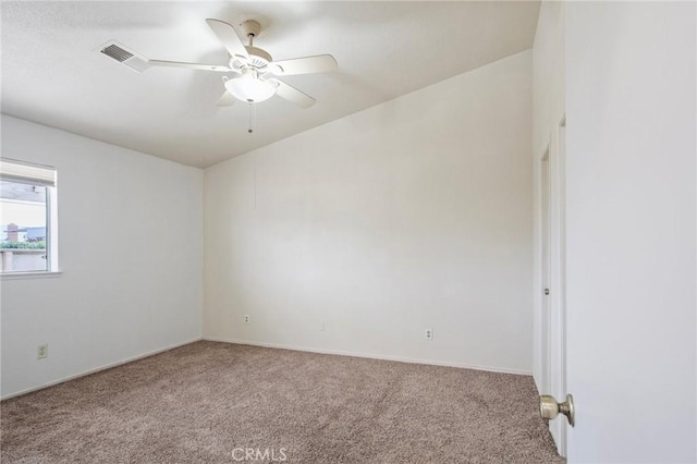 spare room with carpet floors, visible vents, and a ceiling fan