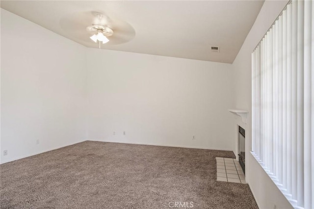 unfurnished living room featuring carpet floors, visible vents, ceiling fan, and a fireplace with flush hearth