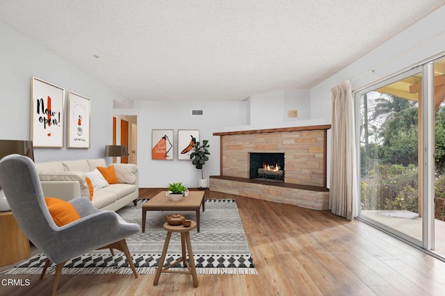 living room with a fireplace, light hardwood / wood-style floors, and a textured ceiling