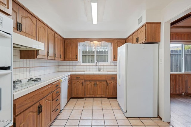 kitchen featuring sink, white appliances, tasteful backsplash, tile counters, and light tile patterned flooring