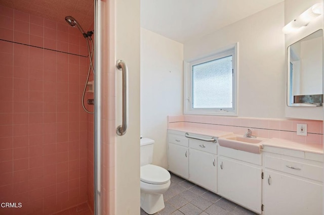 bathroom with tile patterned flooring, vanity, a tile shower, and toilet