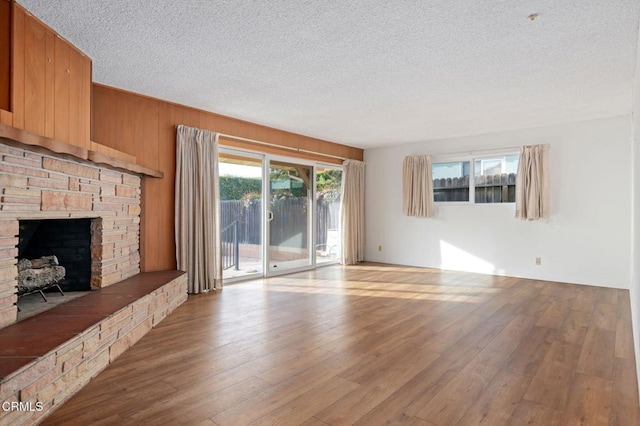 unfurnished living room with a fireplace, light hardwood / wood-style floors, and a textured ceiling