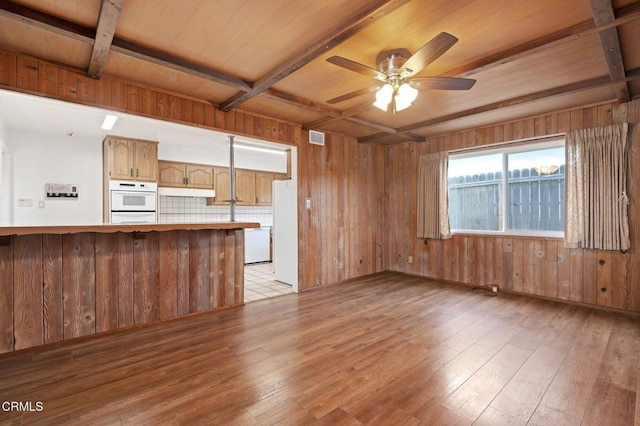 kitchen with wood walls, beam ceiling, kitchen peninsula, and light wood-type flooring