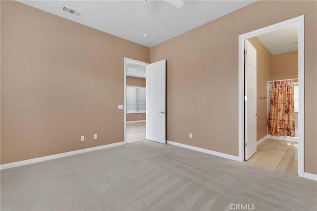 unfurnished bedroom with connected bathroom, light colored carpet, and ceiling fan