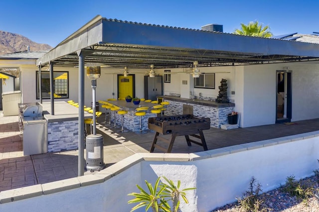 view of patio with exterior bar, area for grilling, and a mountain view