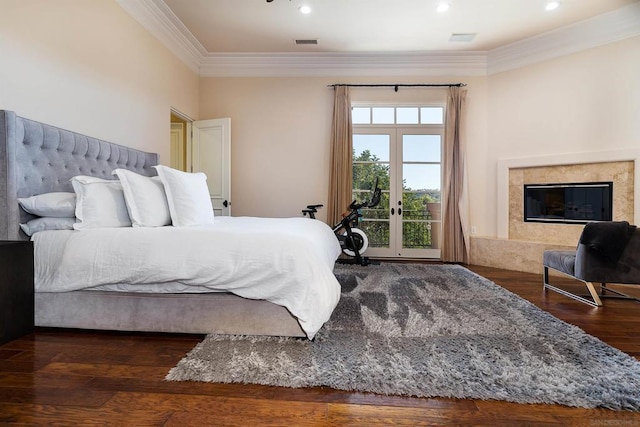 bedroom featuring dark hardwood / wood-style floors, ornamental molding, access to outside, a premium fireplace, and french doors