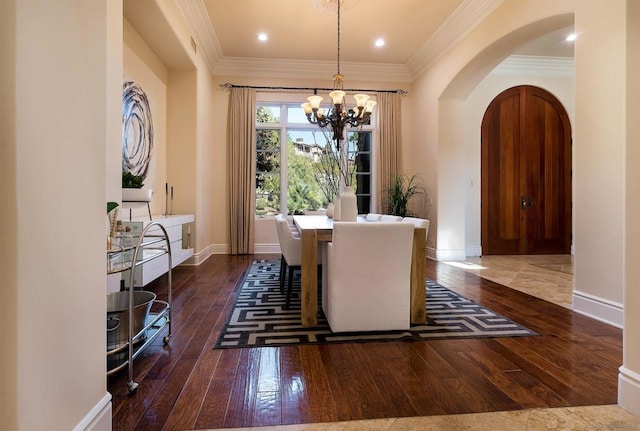 dining space featuring crown molding, a notable chandelier, and dark hardwood / wood-style flooring