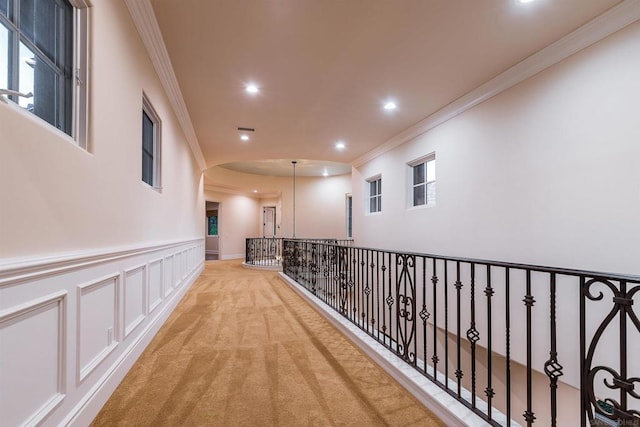 hallway with crown molding and light colored carpet