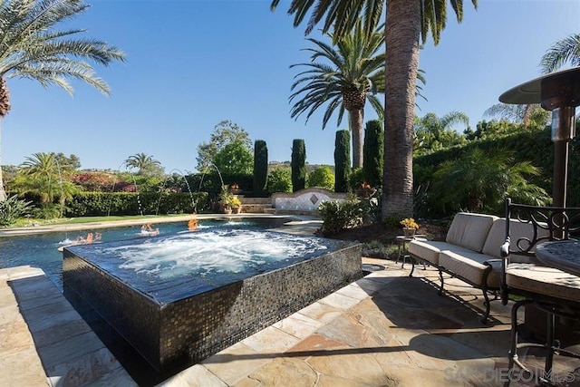 view of pool with a hot tub and a patio