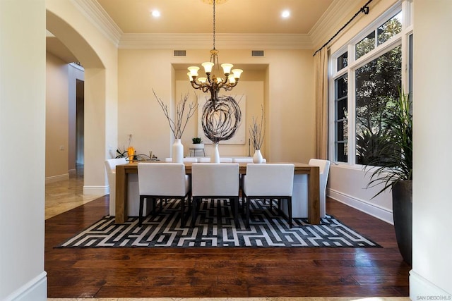 dining area featuring crown molding, dark wood-type flooring, and an inviting chandelier