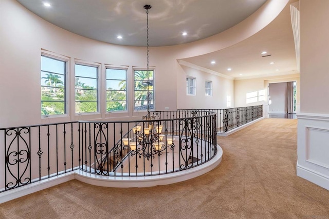 corridor featuring crown molding, a chandelier, and light carpet