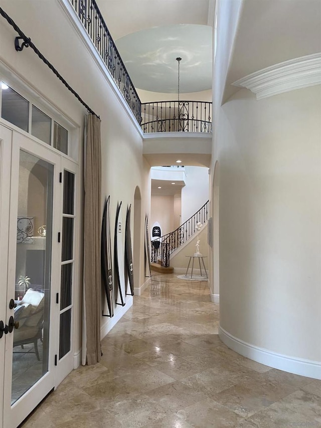 corridor with french doors, a chandelier, and a high ceiling