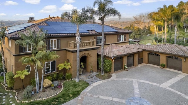 mediterranean / spanish home featuring a balcony, a garage, and solar panels