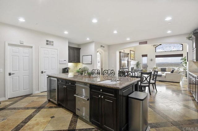 kitchen featuring beverage cooler, sink, and a center island with sink