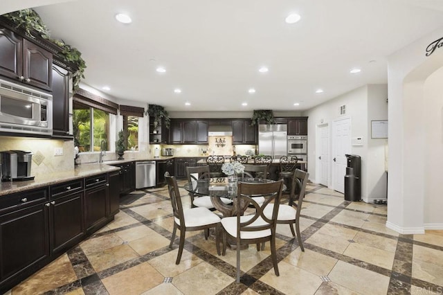 kitchen featuring dark brown cabinets, built in appliances, and decorative backsplash