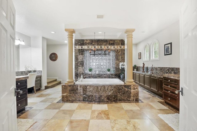 bathroom with vanity, decorative columns, and tiled bath