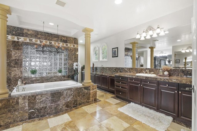 bathroom featuring tile walls, vanity, a tray ceiling, tiled bath, and decorative columns