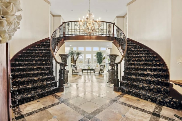 entryway with a notable chandelier, crown molding, and a towering ceiling