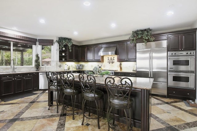 kitchen featuring sink, extractor fan, tasteful backsplash, appliances with stainless steel finishes, and a kitchen island