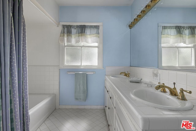 bathroom featuring vanity, plenty of natural light, a washtub, and tile patterned floors