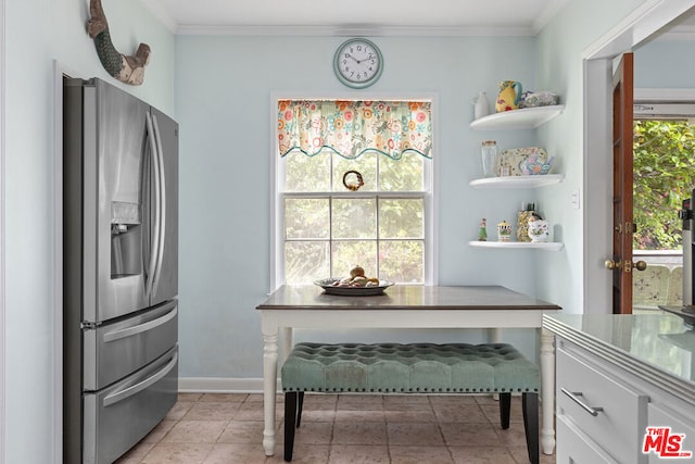 interior space with white cabinetry, a wealth of natural light, stainless steel fridge, and ornamental molding