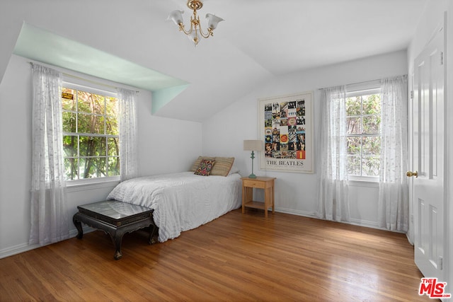 bedroom with lofted ceiling, an inviting chandelier, and light hardwood / wood-style flooring