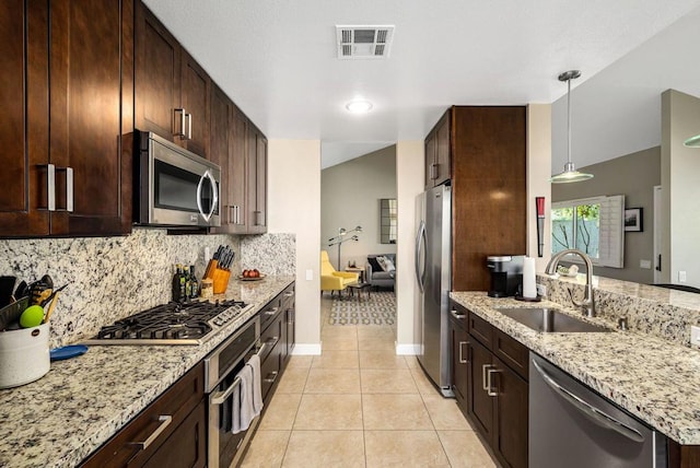 kitchen featuring light tile patterned flooring, sink, light stone counters, hanging light fixtures, and stainless steel appliances