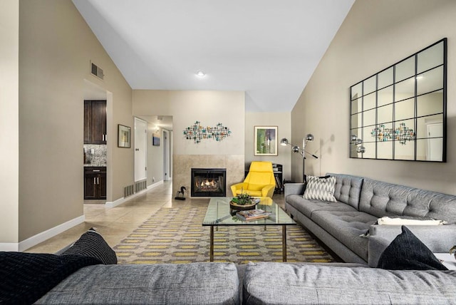 tiled living room featuring a tiled fireplace and high vaulted ceiling