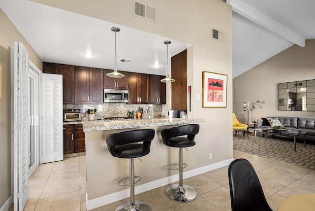 kitchen with pendant lighting, light tile patterned floors, a breakfast bar area, light stone countertops, and kitchen peninsula