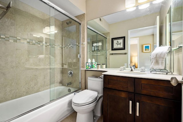 full bathroom featuring toilet, vanity, and bath / shower combo with glass door