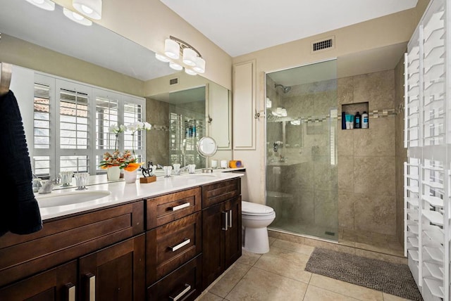 bathroom featuring vanity, tiled shower, tile patterned floors, and toilet