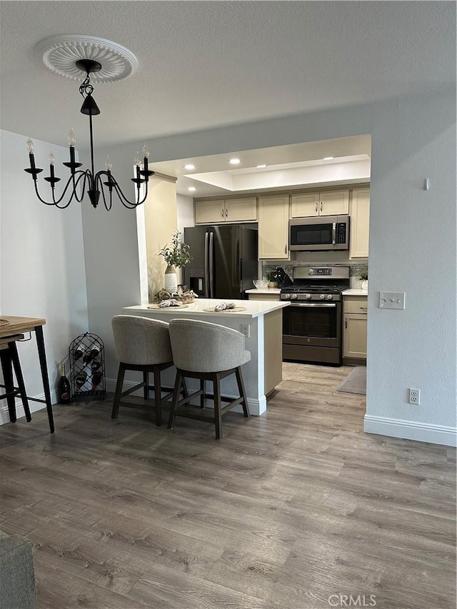 kitchen featuring stainless steel appliances, a kitchen bar, kitchen peninsula, and light hardwood / wood-style flooring