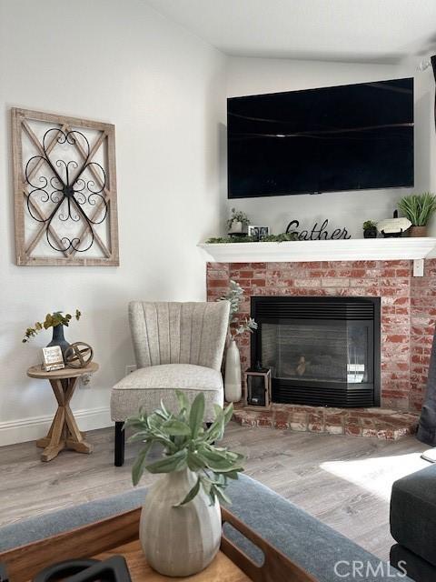 living area featuring a brick fireplace and hardwood / wood-style floors