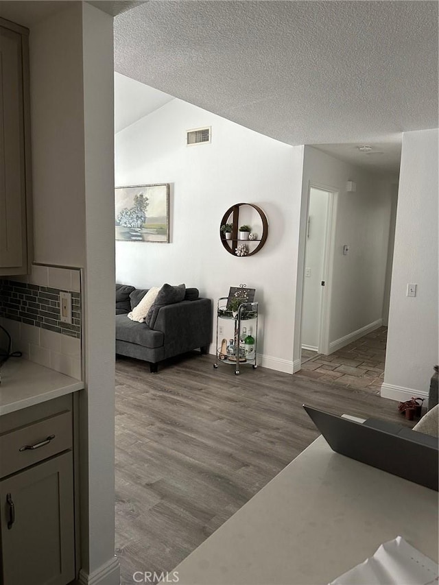 living room featuring lofted ceiling, light hardwood / wood-style flooring, and a textured ceiling