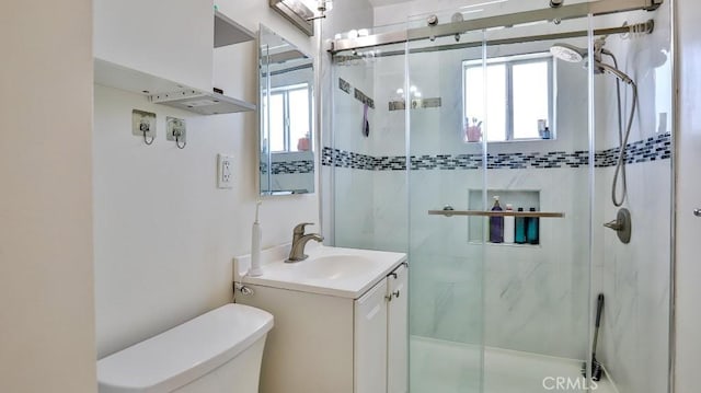 bathroom with vanity, a shower with door, and toilet