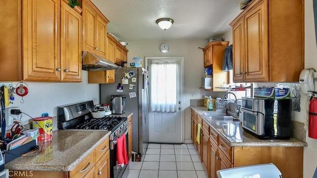 kitchen featuring light stone counters, sink, gas range, and light tile patterned floors