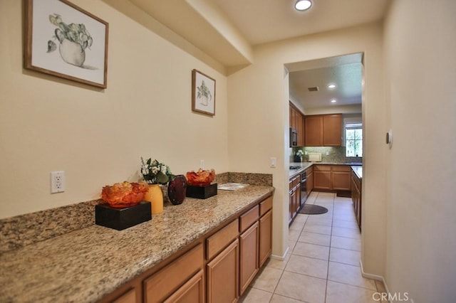 kitchen featuring tasteful backsplash, light stone countertops, and light tile patterned floors