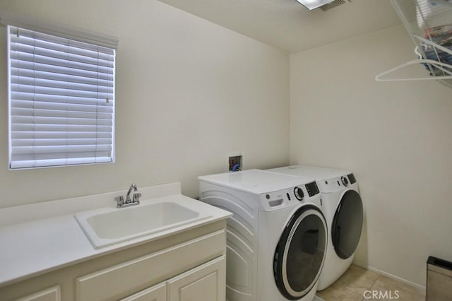 laundry area with cabinets, separate washer and dryer, sink, and light tile patterned floors