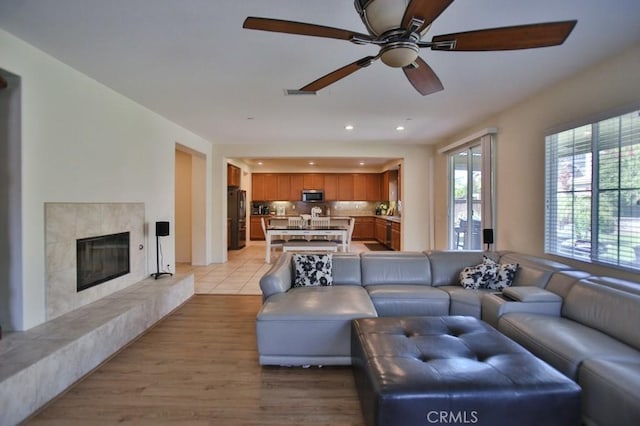 living room with ceiling fan, a fireplace, and light wood-type flooring