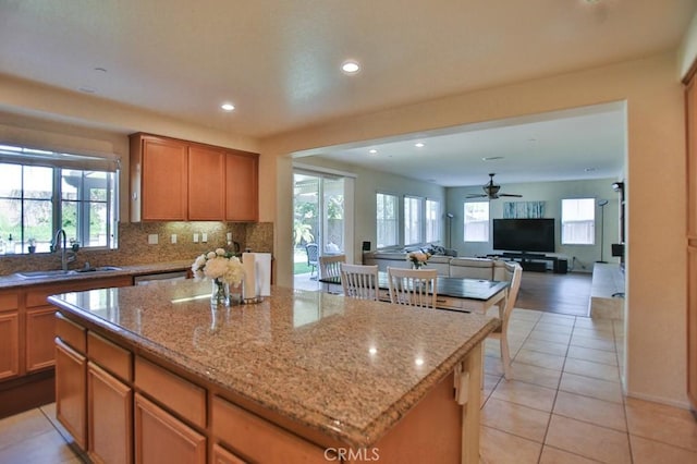 kitchen featuring plenty of natural light, a center island, sink, and light stone countertops