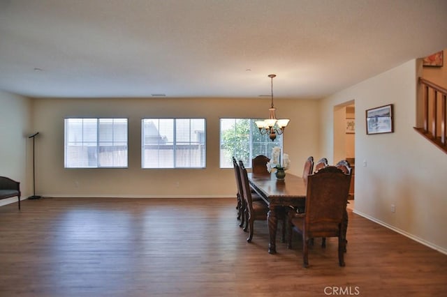 dining space with dark wood-type flooring and an inviting chandelier