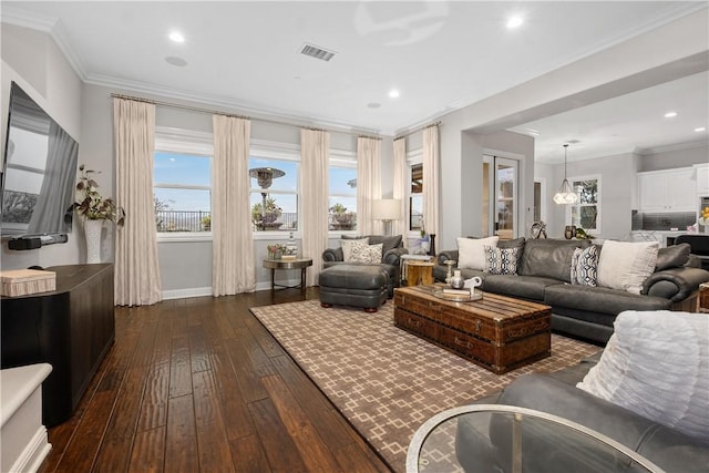 living room with dark wood-type flooring, ornamental molding, and a notable chandelier