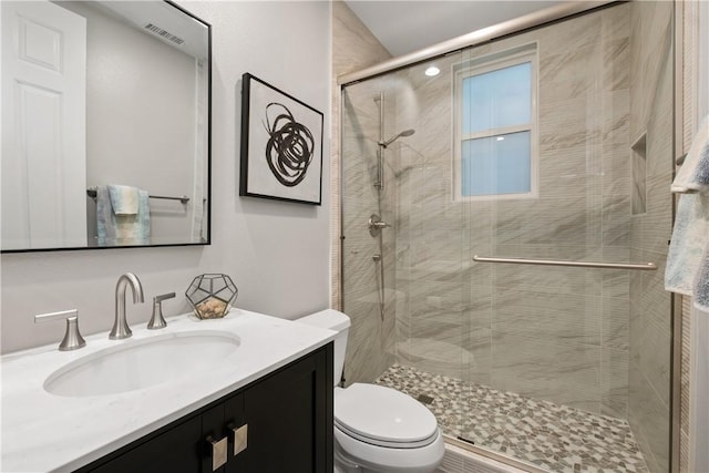 bathroom with vanity, a shower with door, and toilet