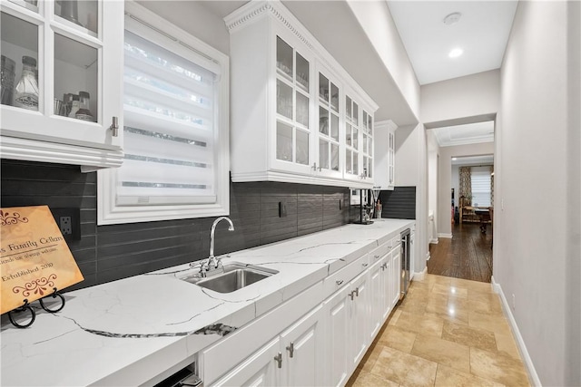 kitchen with tasteful backsplash, light stone countertops, sink, and white cabinets