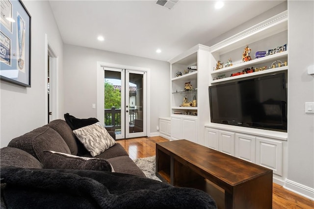 living room featuring built in shelves, light hardwood / wood-style floors, and french doors