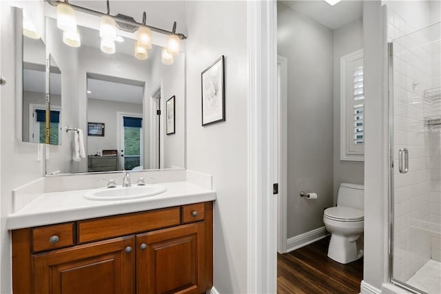 bathroom featuring hardwood / wood-style flooring, vanity, toilet, and a shower with door