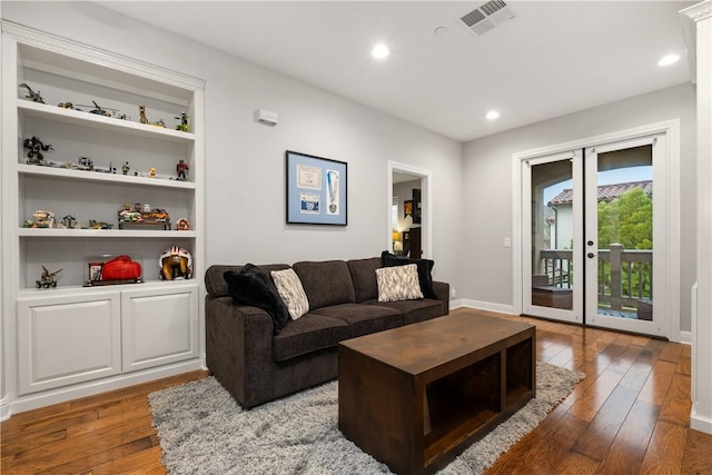 living room with dark wood-type flooring, built in features, and french doors