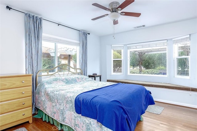 bedroom with multiple windows, hardwood / wood-style flooring, and ceiling fan