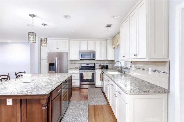 kitchen with white cabinetry, stainless steel appliances, and a kitchen island