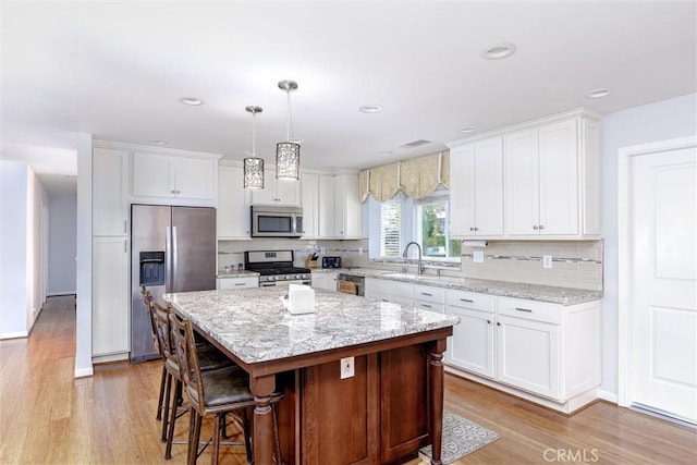 kitchen with white cabinetry, appliances with stainless steel finishes, a center island, and sink